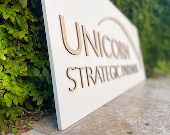 May include: White sign with the text "UNICORN STRATEGIC PARTNERS" in brown wooden letters.