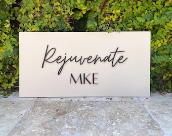 May include: A white rectangular sign with black lettering that reads "Rejuvenate MIKE".