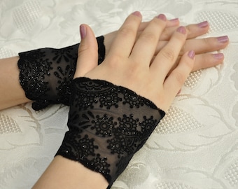 Könnte beinhalten: Ein Paar schwarze fingerlose Handschuhe aus Spitze mit einem glitzernden Design.