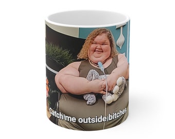 Peut inclure: Une tasse en céramique blanche avec une photo d'une femme aux cheveux blonds tenant un animal en peluche. Le texte "Catch me outside, how 'bout that?" est imprimé au bas de la tasse.