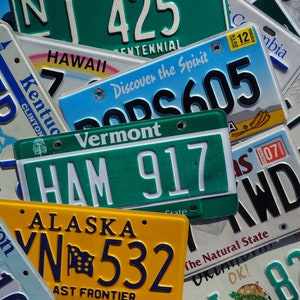 May include: A collection of license plates from different states, including Vermont, Alaska, Oregon, Kentucky, and Hawaii. The plates are arranged in a random order and feature various colors, including green, blue, yellow, and white. The plates display different license plate numbers, state names, and slogans.