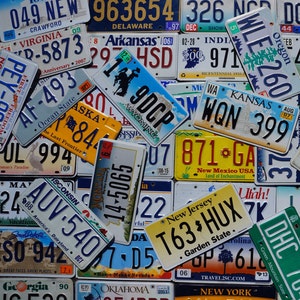 May include: A collection of vintage license plates from different states in the U.S. The plates are in various colors and feature different state names, slogans, and license numbers. Some of the plates are faded and worn, while others are in better condition.