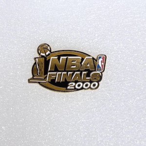 May include: A gold-colored NBA Finals 2000 pin with a basketball, trophy, and the NBA logo. The pin has a black and gold oval border and is set against a white background.
