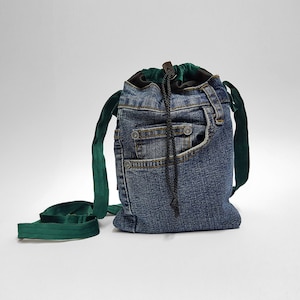 May include: A small denim bag with a green velvet drawstring and shoulder strap. The bag has a large front pocket.