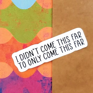 May include: A white sticker with black text that reads "I didn't come this far to only come this far" on a brown envelope with a colorful background.