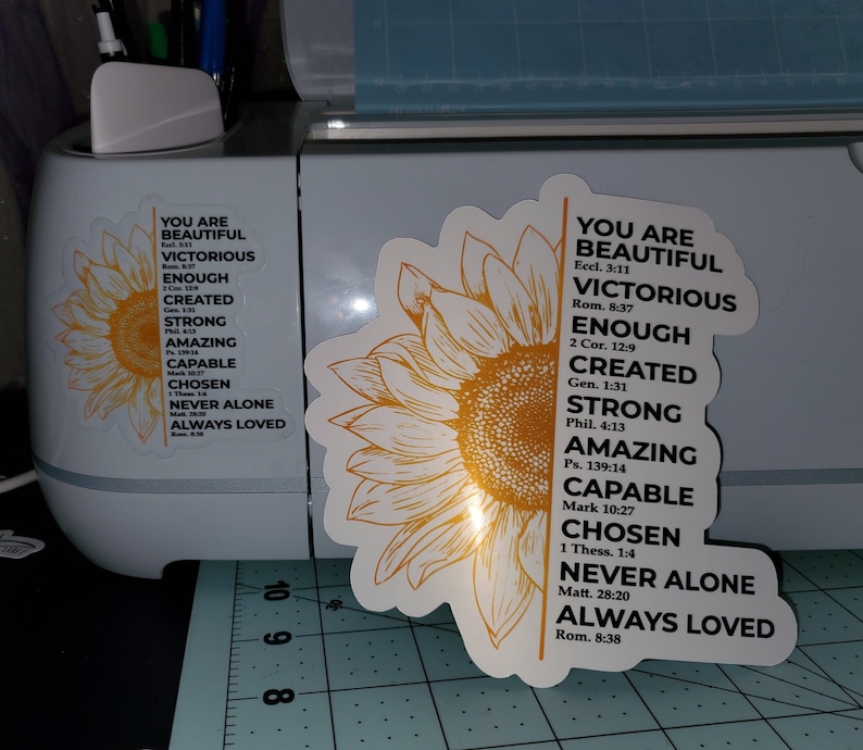 May include: A yellow sunflower with a white outline and a vertical list of positive affirmations with bible verses. The text reads: "You are Beautiful, Victorious, Enough, Created, Strong, Amazing, Capable, Chosen, Never Alone, Always Loved".