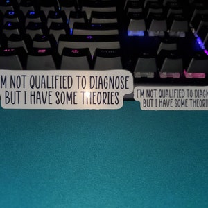 May include: Two white stickers with black text on a blue surface. The text on the stickers reads "I'm not qualified to diagnose but I have some theories."