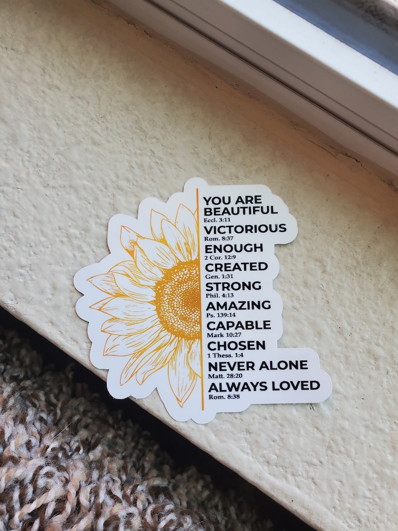 May include: A yellow sunflower sticker with a white border and inspirational text in black. The text reads "You are beautiful, victorious, enough, created, strong, amazing, capable, chosen, never alone, always loved."  Bible verses are listed below each phrase.