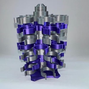 May include: A 3D-printed organizer in silver and purple. The organizer has a central column with multiple tiers of circular holders. The holders alternate between silver and purple, creating a visually appealing design. The base is purple.