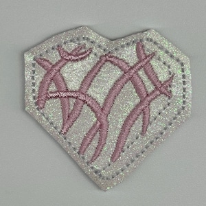 May include: A heart-shaped patch with a glittery white border and a pink embroidered design. The design features intersecting curved lines, creating a textured effect. The patch is likely for clothing or accessories.