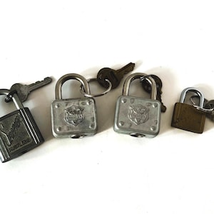 May include: Four vintage silver padlocks with keys. The padlocks have different designs and brands, including "Master" and "Schlage".
