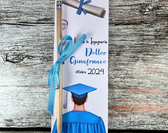 May include: A graduation card with a blue ribbon, a pencil, and a drawing of a person wearing a blue graduation gown and cap. The card says "Dottor Gianfranco ottobre 2024".