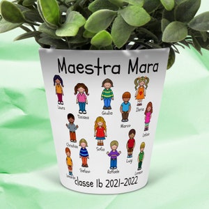 Può includere: Un vaso in ceramica bianca con le parole "Maestra Mara" e "classe Ib 2021-2022" stampate su di esso. Il vaso è decorato con disegni di bambini in stile cartone animato, ognuno con un nome scritto sotto.