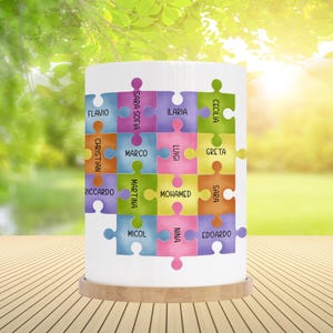 Può includere: Un paralume in ceramica bianca con un design a puzzle colorato con nomi come Flavia, Sara Sofia, Ilaria, Cecilia, Christian, Marco, Luigi, Greta, Riccardo, Martina, Mohamed, Sara, Micol, Nina ed Edoardo.