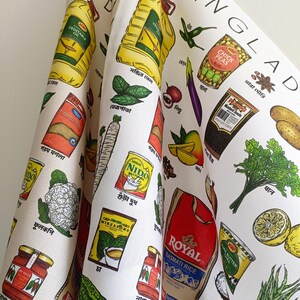 May include: White kitchen towel featuring colorful illustrations of Bangladeshi food items, including vegetables, spices, and packaged goods. The word "BANGLADESH" is printed at the top. The towel has a variety of food illustrations.