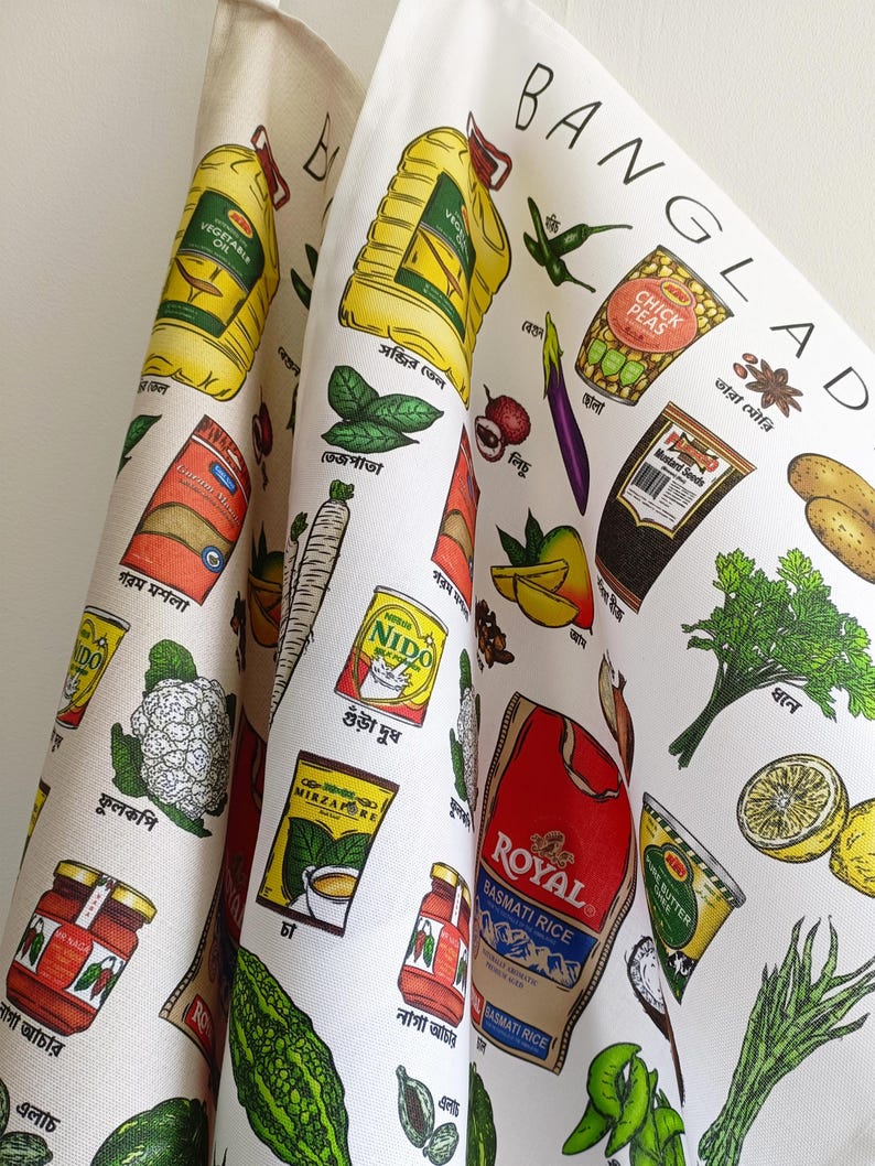 May include: White kitchen towel featuring colorful illustrations of Bangladeshi food items, including vegetables, spices, and packaged goods. The word "BANGLADESH" is printed at the top. The towel has a variety of food illustrations.