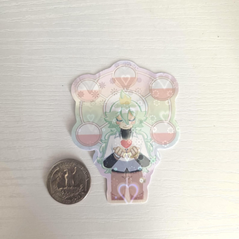 May include: A colorful sticker featuring an anime-style character with green hair, holding a red heart. The sticker has a decorative border with floral and geometric elements. A quarter is next to the sticker for size comparison.