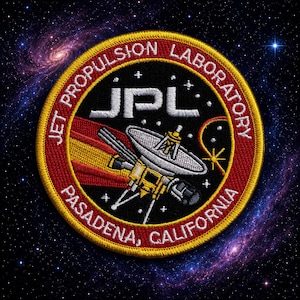 Puede incluir: Un parche bordado circular que presenta el logotipo del Jet Propulsion Laboratory con el texto JPL, Jet Propulsion Laboratory y Pasadena, California. El diseño incluye una sonda satelital plateada sobre un fondo negro con bordes rojos.