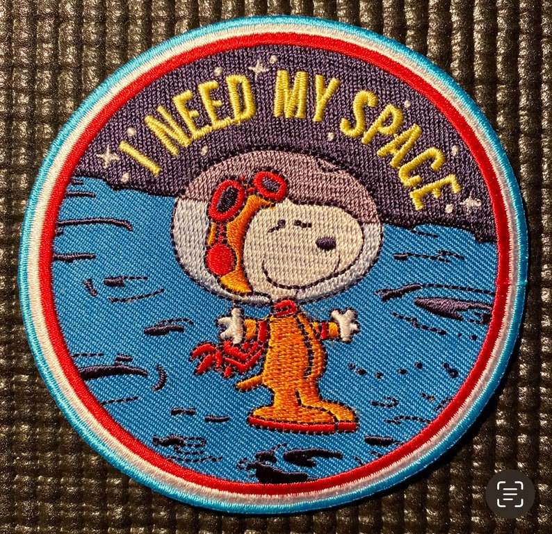 May include: A blue and red embroidered patch with a cartoon dog wearing goggles and a spacesuit. The text "I need my space" is embroidered in white on the patch.
