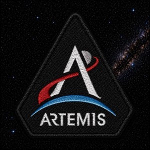 May include: Black embroidered patch with the Artemis program logo. The design features a white stylized letter "A" with a red and blue arc, and the word "ARTEMIS" in white text below. The background depicts a starry night sky.