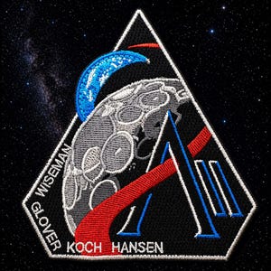 Pode incluir: Patch bordado com um design triangular. Apresenta uma lua estilizada, um arco azul e uma letra "A" estilizada vermelha e azul. O patch inclui os nomes GLOVER, WISEMAN, KOCH e HANSEN. Em um fundo preto com um céu estrelado.