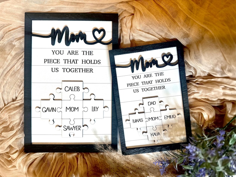 May include: Two framed wood signs with the text "Mom You are the piece that holds us together" and a heart. Each sign has a puzzle piece design with names on each piece.