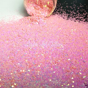 May include: Pink iridescent glitter with a holographic finish. The glitter is loose and has a fine texture.