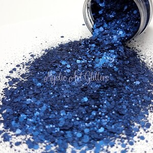 May include: A close-up of a pile of blue glitter, with a variety of sizes and shapes. The glitter is spilling out of a jar, and the background is white.