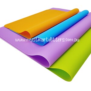 May include: Four sheets of colourful craft foam in orange, blue, purple, and green. The sheets are folded and stacked on top of each other. The text "www.mysticartglitters.com.au" is visible on the bottom sheet.