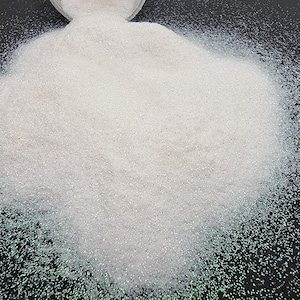 May include: A generous scattering of white glitter on a black surface. The glitter particles are small and reflect light, producing a shimmering effect. The image is a close-up, emphasising the texture and sparkle of the glitter, suitable for crafts.