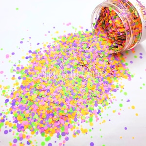 May include: A jar of colourful round glitter in shades of green, yellow, pink, and purple. The glitter is spilling out of the jar onto a white surface.