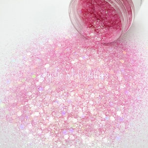 May include: Pink iridescent glitter with a variety of sizes and shapes. The glitter is loose and spilling out of a clear jar.