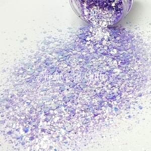 May include: A close-up of a jar of iridescent purple and white glitter. The glitter is spilling out of the jar and creating a shimmering pile.