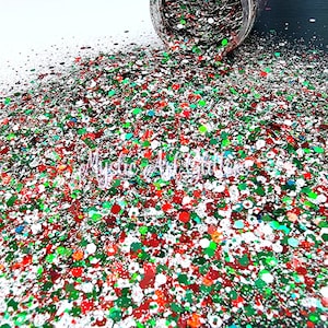 May include: A close-up of a pile of red, green, white and silver glitter. The glitter is scattered on a white surface.