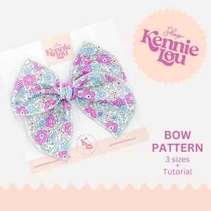 May include: A floral patterned bow on a white card. The bow features a design of pink and blue flowers on a white background. The card has the text "Shop Kennie Lou" and "Bow Pattern" with "3 sizes + Tutorial".
