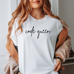 May include: White t-shirt with the text "code queen" written in black cursive script.