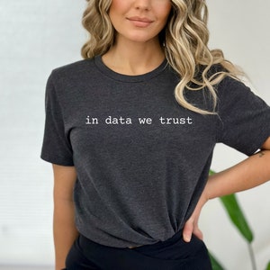 May include: A dark gray t-shirt with the text "in data we trust" printed in white on the front.