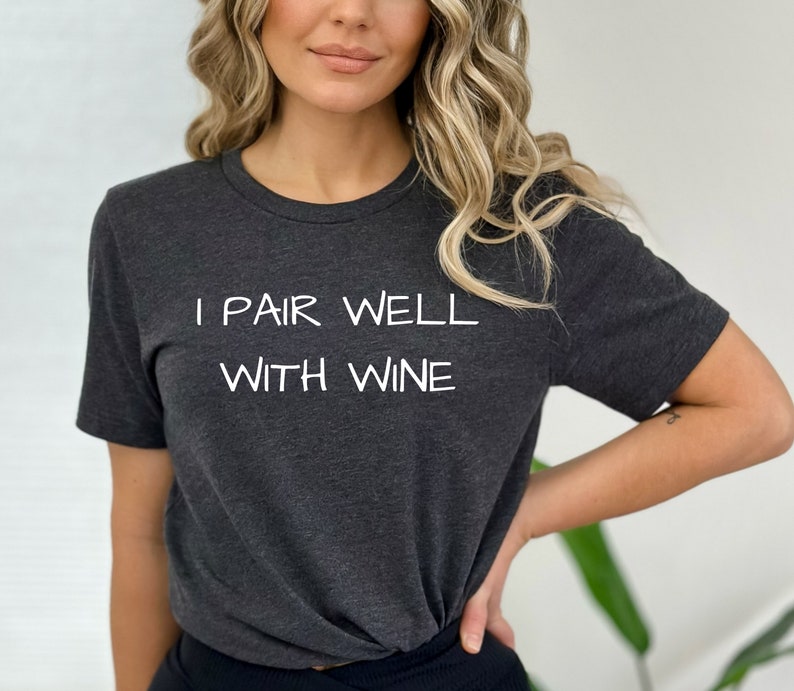 May include: A dark gray t-shirt with the text "I pair well with wine" printed in white.