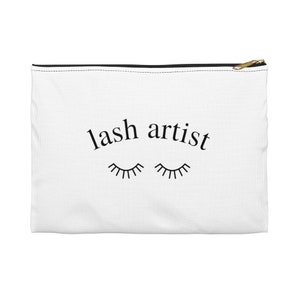 Könnte beinhalten: Weiße Canvas-Kosmetiktasche mit schwarzem Text "lash artist" und zwei stilisierten Wimpern.