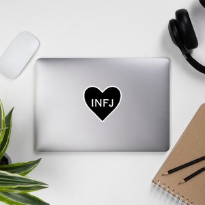 May include: Black and white sticker with a heart shape and the text "INFJ" inside.