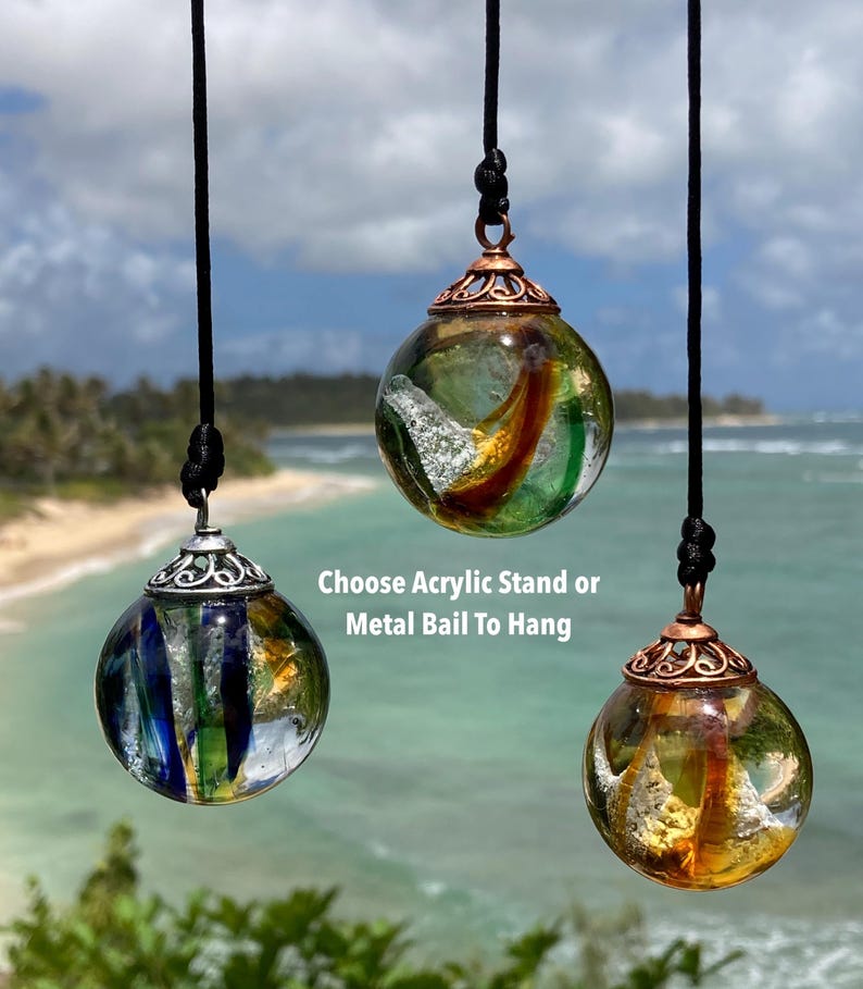 Pode incluir: Tr&ecirc;s pingentes de globo de vidro com designs internos coloridos, suspensos por cord&otilde;es pretos. Os globos t&ecirc;m tampas de metal e s&atilde;o exibidos em um cen&aacute;rio de praia. O texto diz "Choose Acrylic Stand or Metal Bail To Hang."