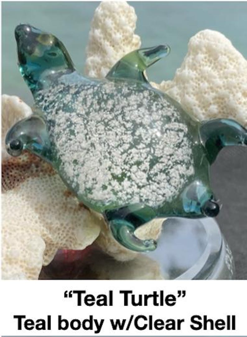 Pode incluir: Uma estatueta de tartaruga de vidro verde-azulado com uma carapa&ccedil;a transparente. A tartaruga tem um design detalhado com barbatanas, cabe&ccedil;a e cauda. A carapa&ccedil;a tem um padr&atilde;o salpicado branco. A estatueta &eacute; exibida em uma superf&iacute;cie branca semelhante a coral.