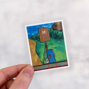 May include: A sticker featuring a hand-painted illustration of a hiking trail sign with the text "Highline Trail" and a blue backpack with hiking poles. The sticker has the text "GLACIER NTL. PARK" at the bottom.