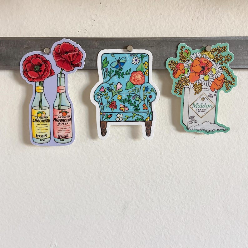 Pode incluir: Tr&ecirc;s adesivos com designs florais. O primeiro adesivo mostra duas garrafas de refrigerante italiano com flores vermelhas. O segundo adesivo mostra uma poltrona azul com um padr&atilde;o floral. O terceiro adesivo mostra uma caixa de flocos de sal marinho Maldon com um buqu&ecirc; de flores vermelhas e brancas.