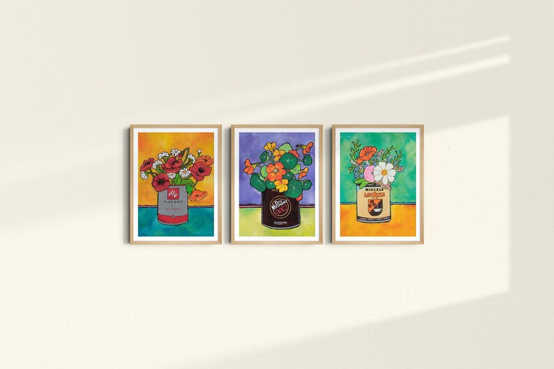 Puede incluir: Tres impresiones enmarcadas de arreglos florales en latas vintage. La primera impresi&oacute;n presenta flores rojas en una lata azul y roja etiquetada "Claussen Pickles". La segunda impresi&oacute;n presenta flores naranjas en una lata marr&oacute;n etiquetada "Wieners". La tercera impresi&oacute;n presenta flores rosas y blancas en una lata amarilla y naranja etiquetada "Miracle Whip Salad Dressing".
