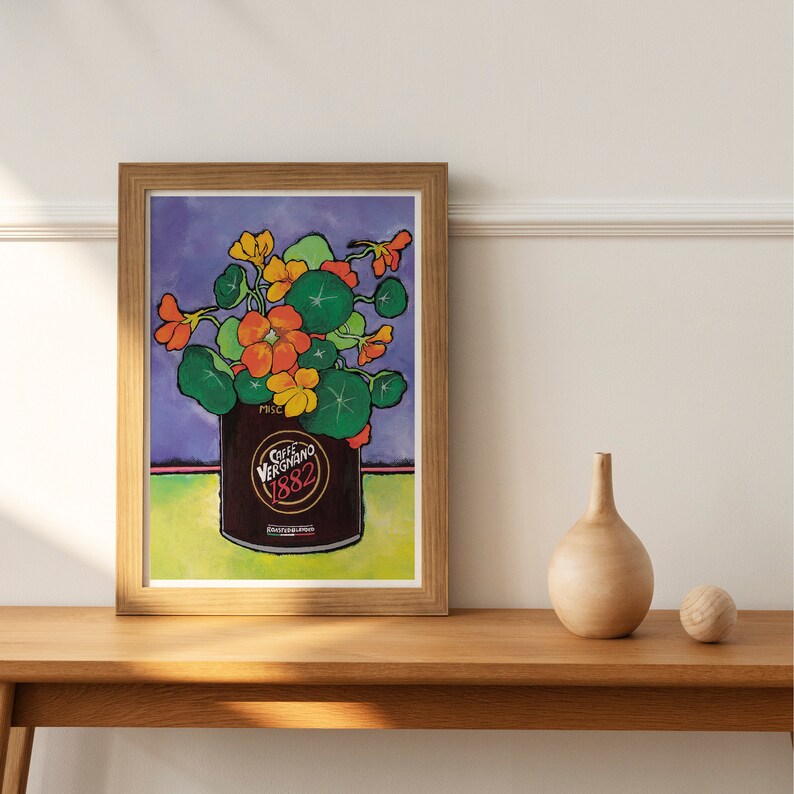 Puede incluir: Una impresi&oacute;n enmarcada de una pintura que representa un ramo colorido de flores naranjas y amarillas en una lata marr&oacute;n con el texto "Caffe Vergnano 1882". Las flores est&aacute;n en un jarr&oacute;n sobre un fondo morado.