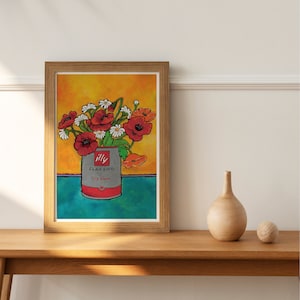 Pu&ograve; includere: Un dipinto ad acquerello incorniciato di un bouquet di fiori rossi e bianchi in una lattina grigia con il testo "illy Classico illy blend" su uno sfondo giallo e blu.