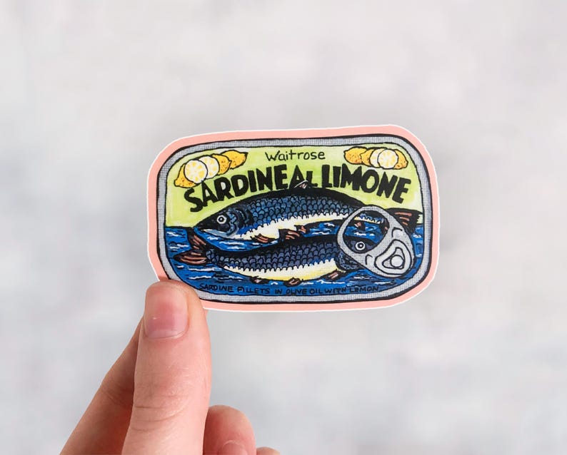 Puede incluir: Una pegatina rosa y amarilla con una ilustraci&oacute;n de dibujos animados de una lata de sardinas. La lata dice "Waitrose Sardine al Limone" y "Sardine fillets in olive oil with lemon".
