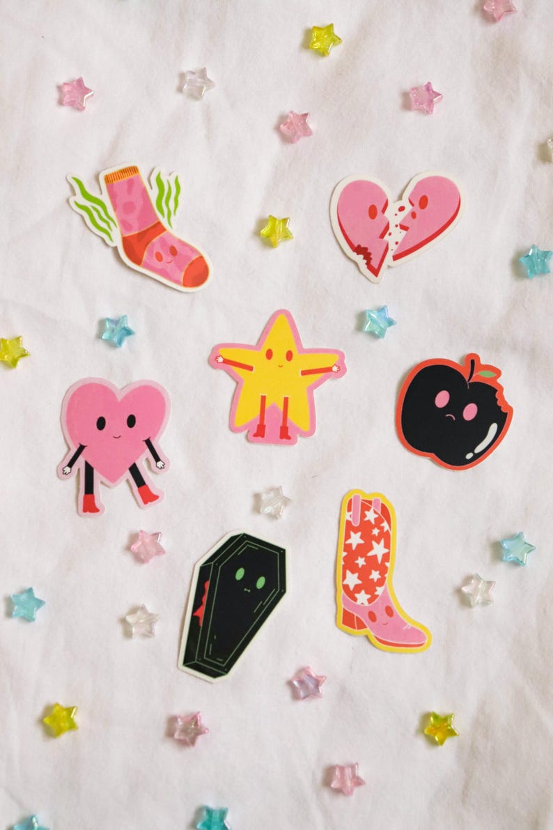 May include: A set of eight colorful stickers featuring various characters, including a sock, a broken heart, a star, an apple, a heart, a coffin, and a cowboy boot. The stickers are on a white background.