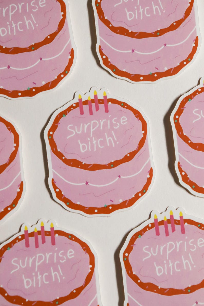 May include: Pink cake stickers with the text "Surprise bitch!" in white script. The stickers have a red border with sprinkles and candles. The stickers are a fun and playful design.